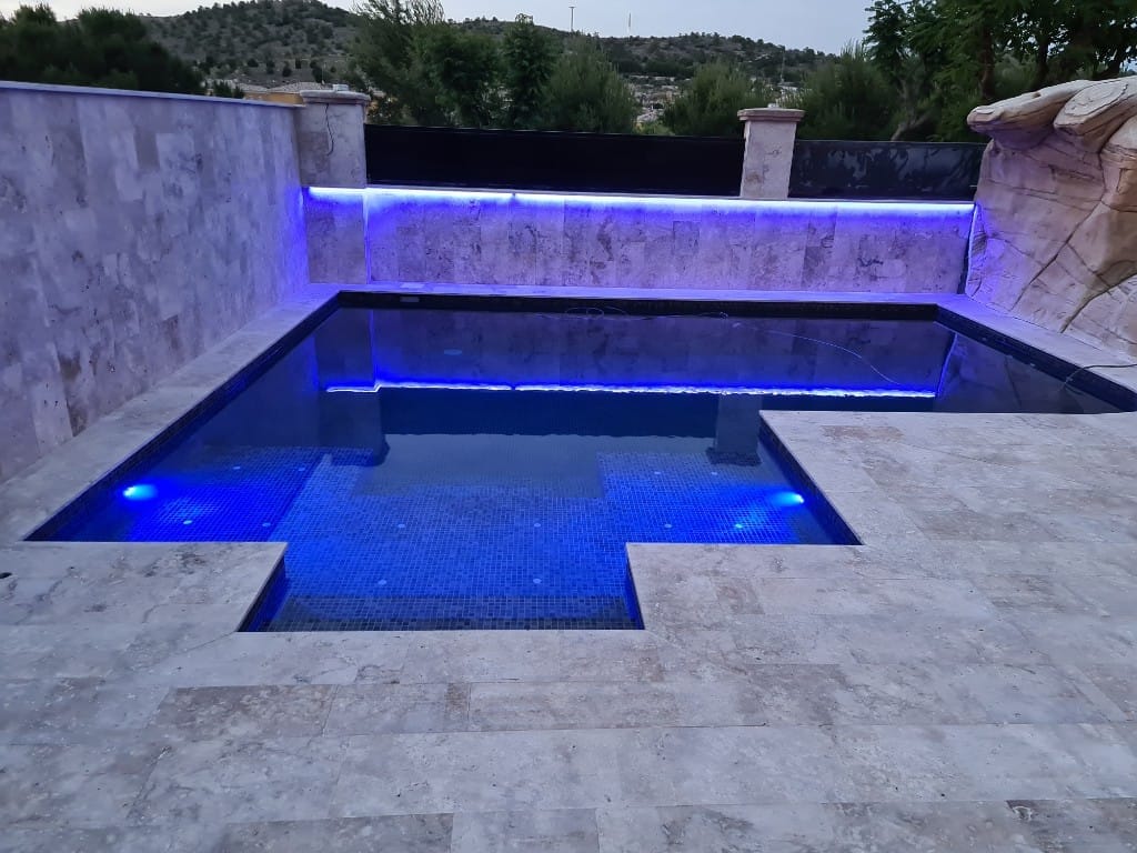 Piscina con iluminación LED azul intenso al atardecer
