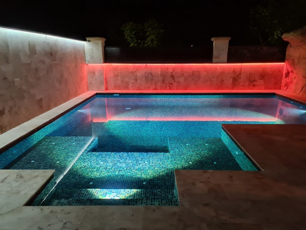Piscina con iluminación cálida ámbar y agua azul de noche